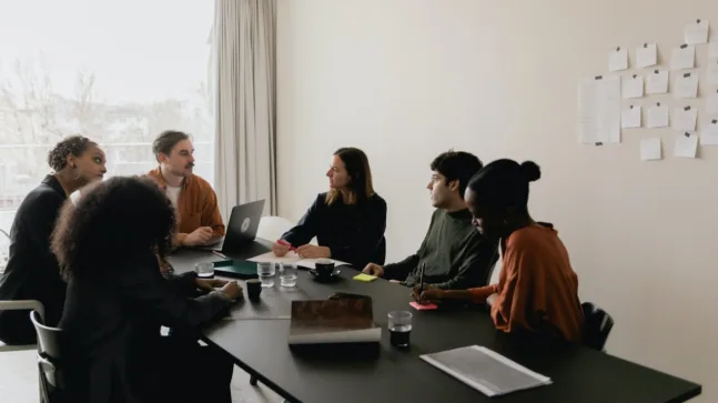 A group of people in a bright office discussing a project